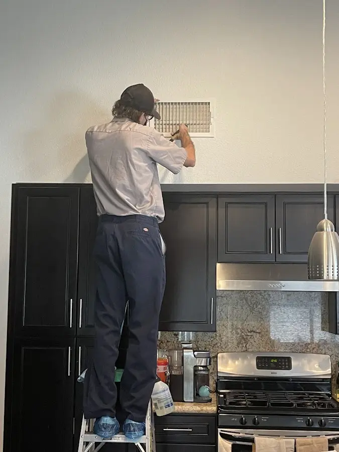 Technician inspecting an air vent during HVAC service in Brooklyn
